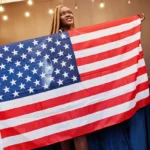 An African American woman proudly holds the American flag for Juneteenth.