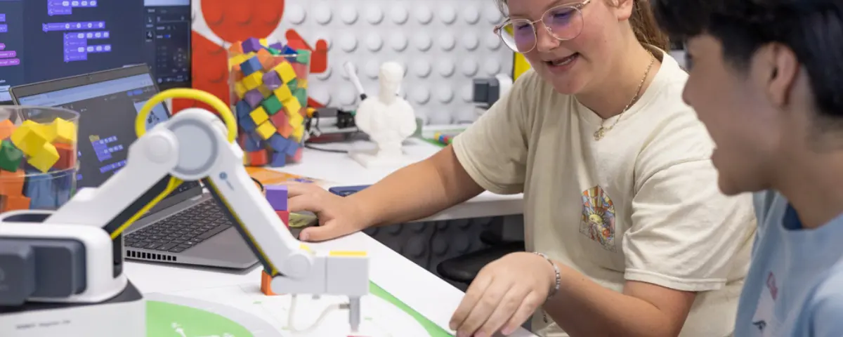Students interacting with a Dobot in a classroom.