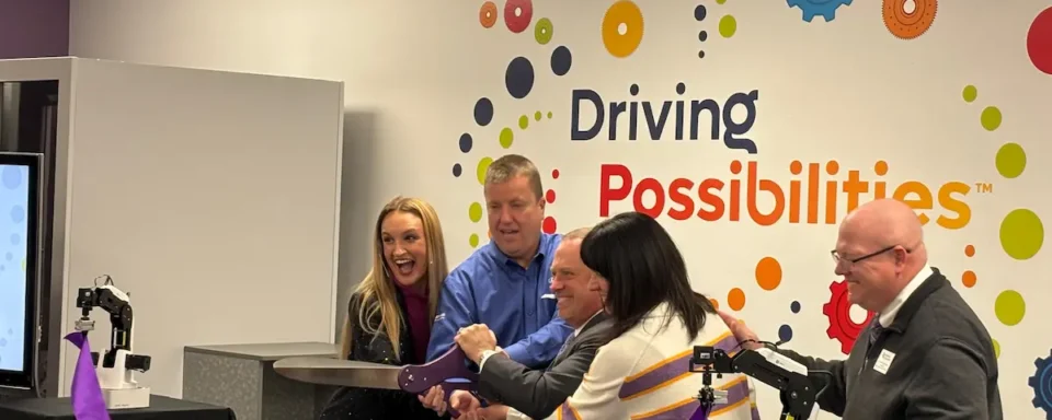 Collaborators from the University of Evansville, STEM Education Works, and Purdue In-MaC hold giant scissors at a ribbon cutting for the new Design and Innovation Studio.