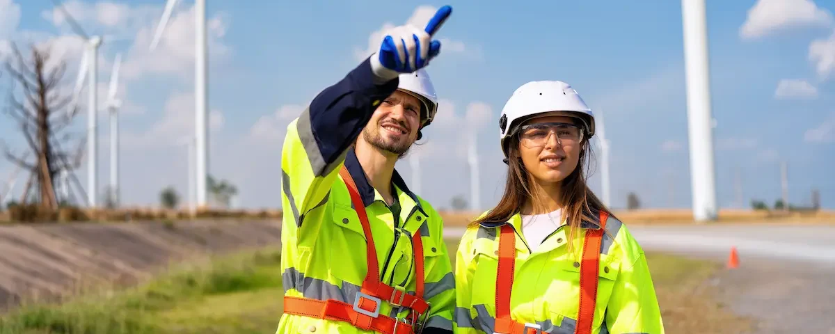 A man and woman working in the environmental industry point to a windmill to demonstrate the importance of STEM education and workforce readiness.