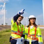 A man and woman working in the environmental industry point to a windmill to demonstrate the importance of STEM education and workforce readiness.