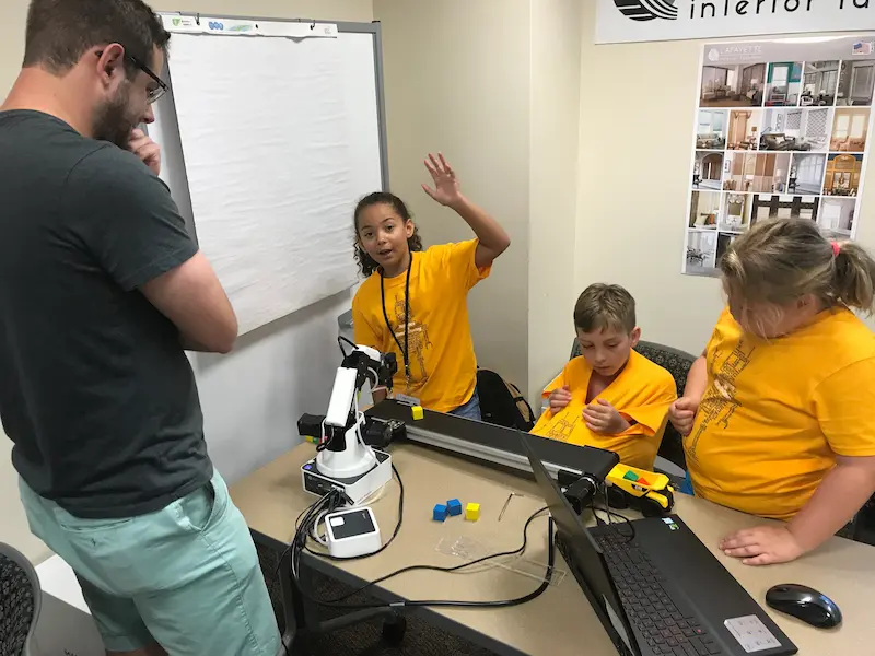  A child raises their hand during a robotics summer camp