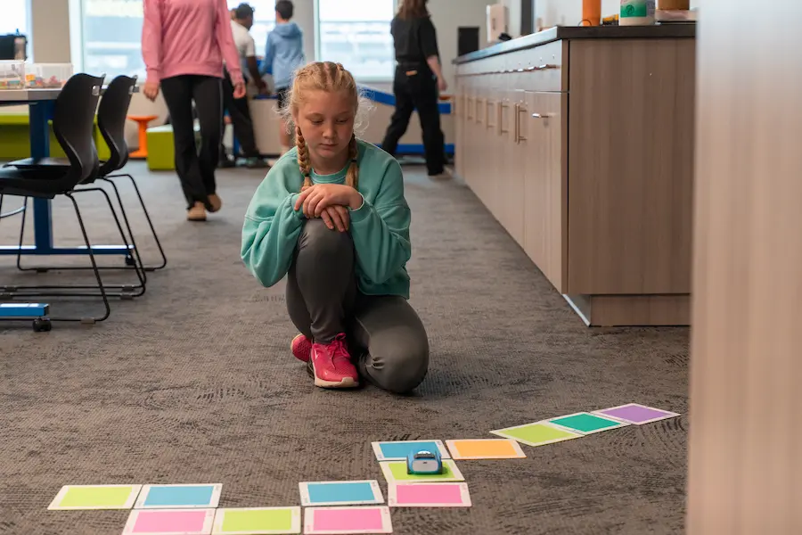 Young girl at the museum STEM exhibit working with Sphero indi car