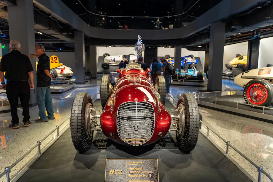 An interior shot of a museum exhibit that includes vintage Indy 500 cars
