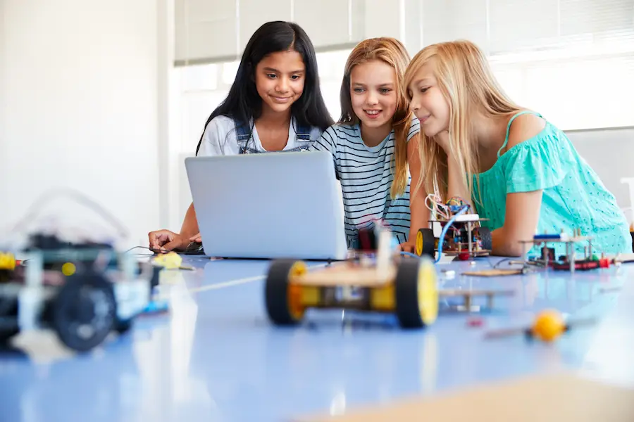 Three girls build a robot together in honor of Women in Engineering Day. 
