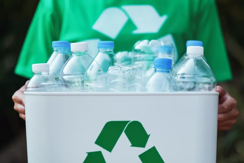 a woman collecting garbage and holding a recycle bin