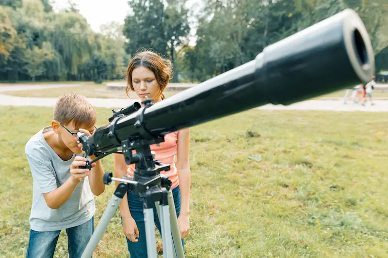  Kids celebrate National Moon Day by looking through their telescope. 