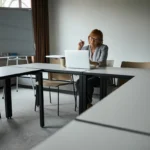 An educator sits in an empty classroom, searching for STEM education grants on her laptop.