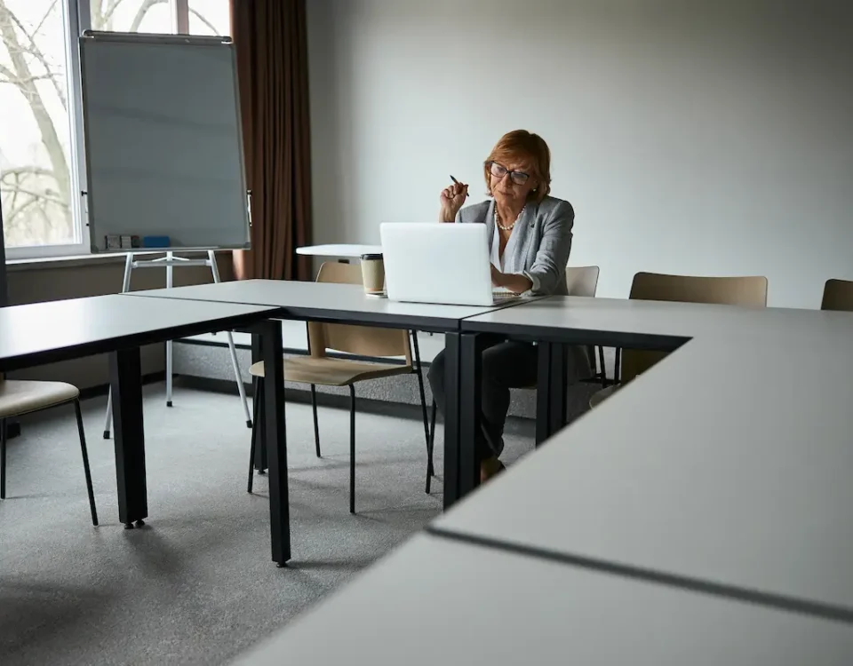 An educator sits in an empty classroom, searching for STEM education grants on her laptop.