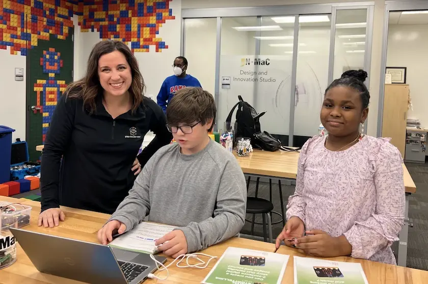 Students working on a laptop and micro:bit with an instructor