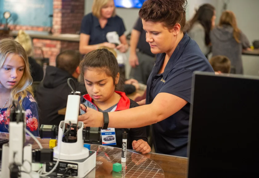 A teacher instructs her students on using a Dobot
