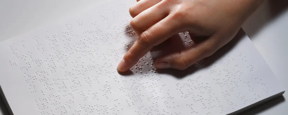Child reading braille in a classroom.