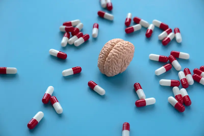 Small brain surrounded by red and white pills
