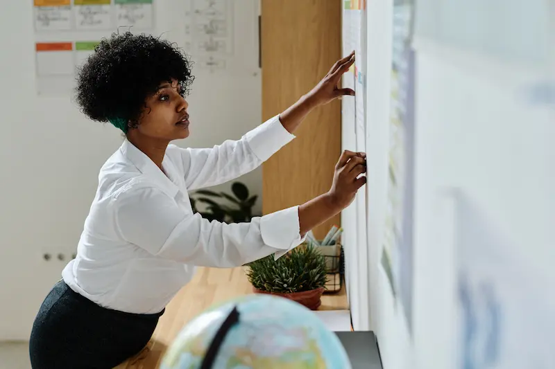 Teacher writing on a blackboard in a classroom.