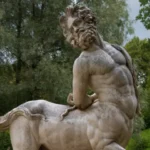 Marble statue of a male centaur leaning backwards.