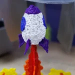 Colorful 3D printed rocket supported by 3D printed flames.