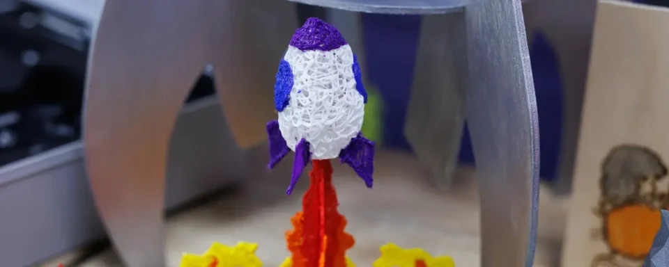 Colorful 3D printed rocket supported by 3D printed flames.