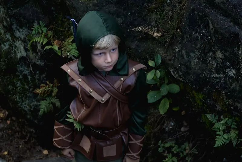 Boy in a medieval outfit in the forest.