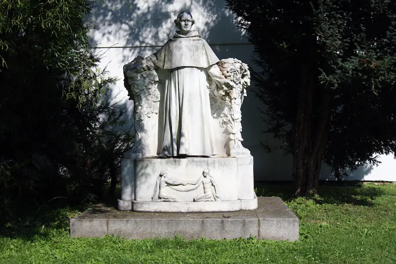 Marble statue of Gregor Mendel wearing a monk robe and hood. 