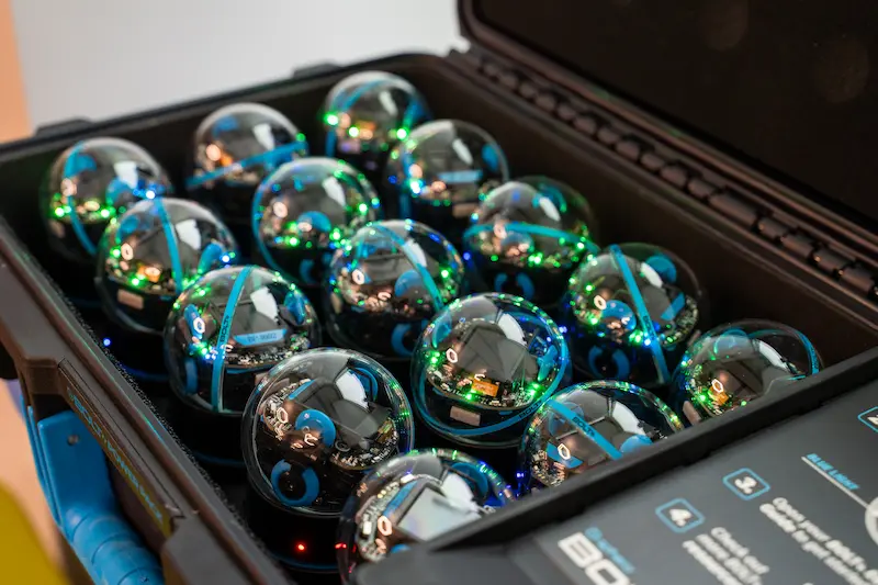 Several Sphero BOLT robots in their storage case.
