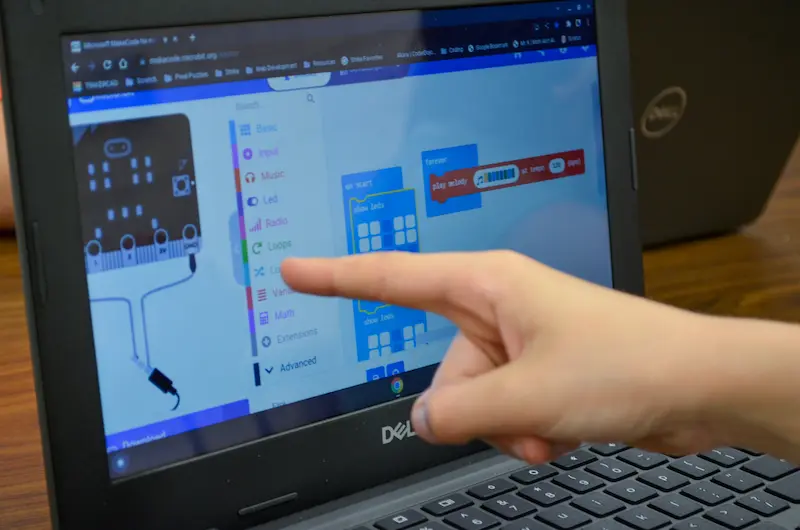 Student pointing at a block of code on a computer screen while working on programming a micro:bit.