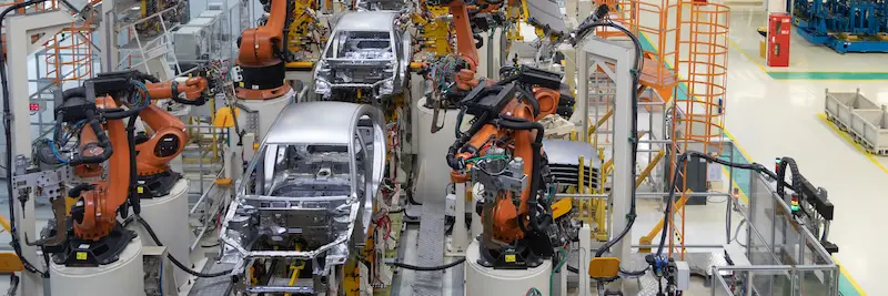 Multiple automated robotic arms assembling a car body in an automotive factory.