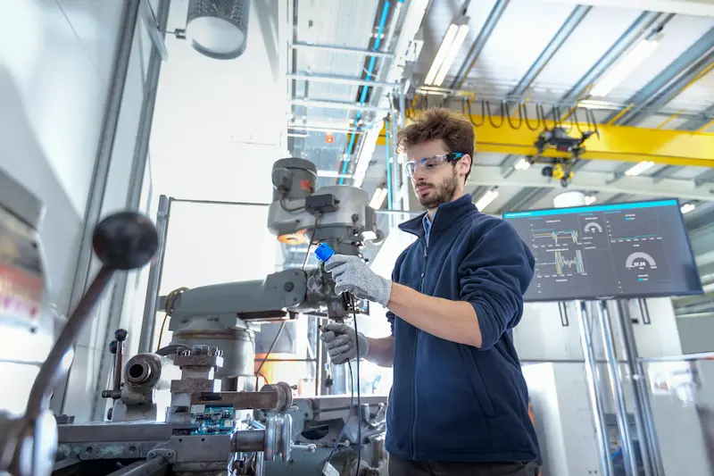 Worker wearing safety glasses connecting a cable to a machine.