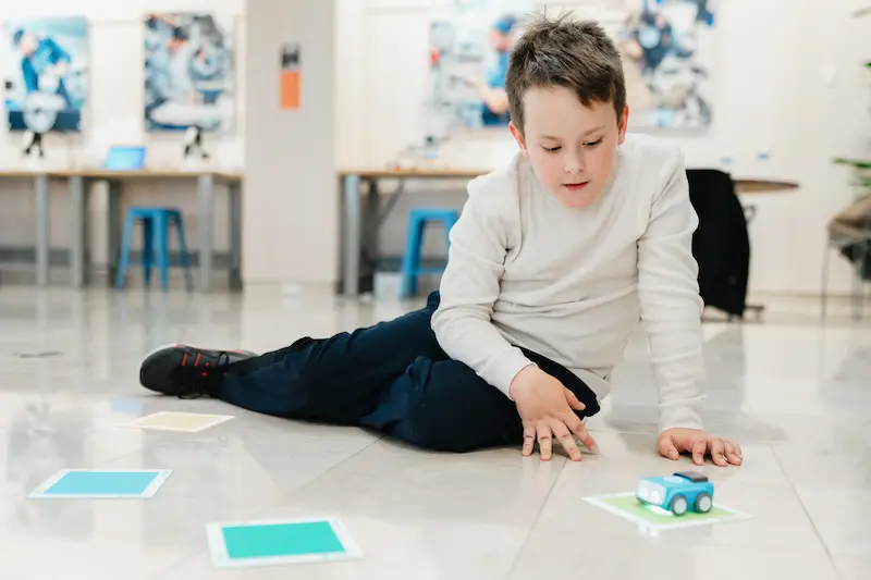 Boy watching a Sphero Indi robot travel from one colored card to another