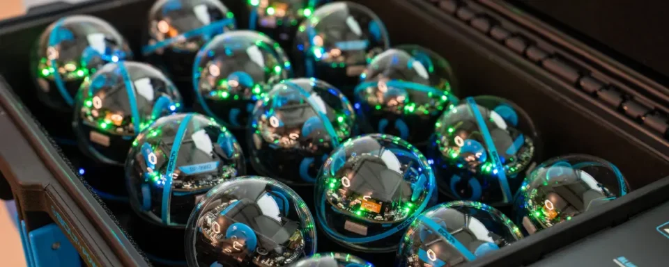 Several BOLT+ robots in a blue storage case that charges the robots.