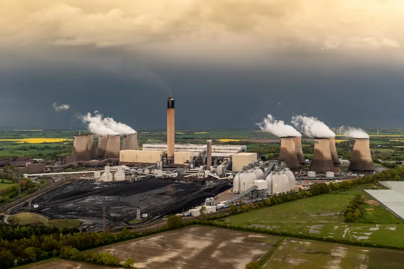 Industrial power plant with white vapor coming out of multiple cooling towers.