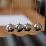 Closeup of a Newton’s cradle on a wooden desk.