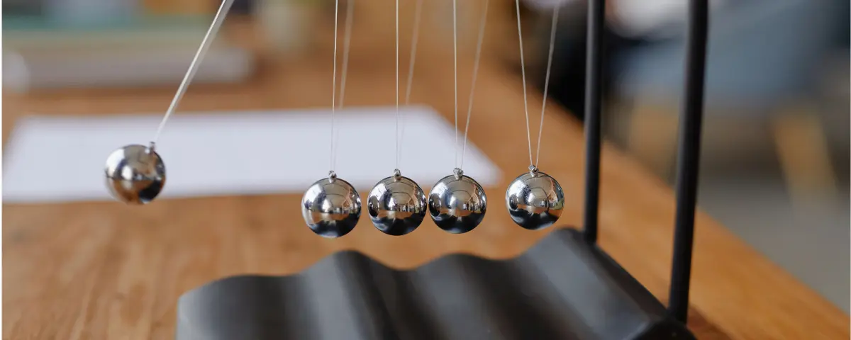 Closeup of a Newton’s cradle on a wooden desk.