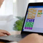 Child learning programming using block coding on a laptop.