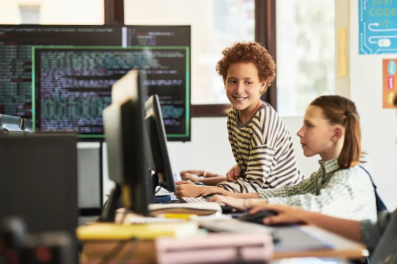 Students learning computer programming by coding in a classroom.