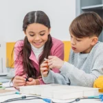 Four children working on a robotics project in the classroom.