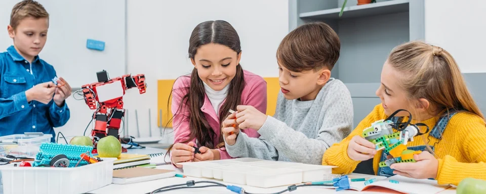 Four children working on a robotics project in the classroom.