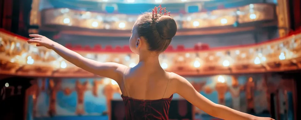 Girl in ballerina outfit standing in the spotlight on a theater stage.