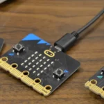 Three micro:bits attached to USB charging cables on a table.
