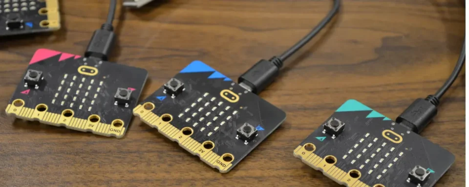 Three micro:bits attached to USB charging cables on a table.