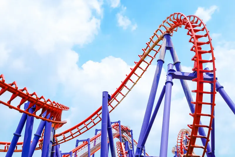 A bright red roller coaster loop with a blue sky in the background.