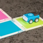 A Sphero Indi robot on carpet traveling on a path made up of multi-colored cards.