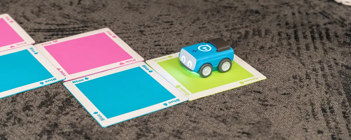 A Sphero Indi robot on carpet traveling on a path made up of multi-colored cards.