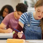Student feeling stressed while taking a test on paper in a classroom.