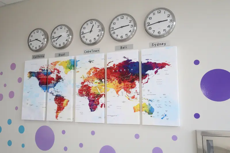 Colorful map that displays world time zones with clocks for major cities across the world.