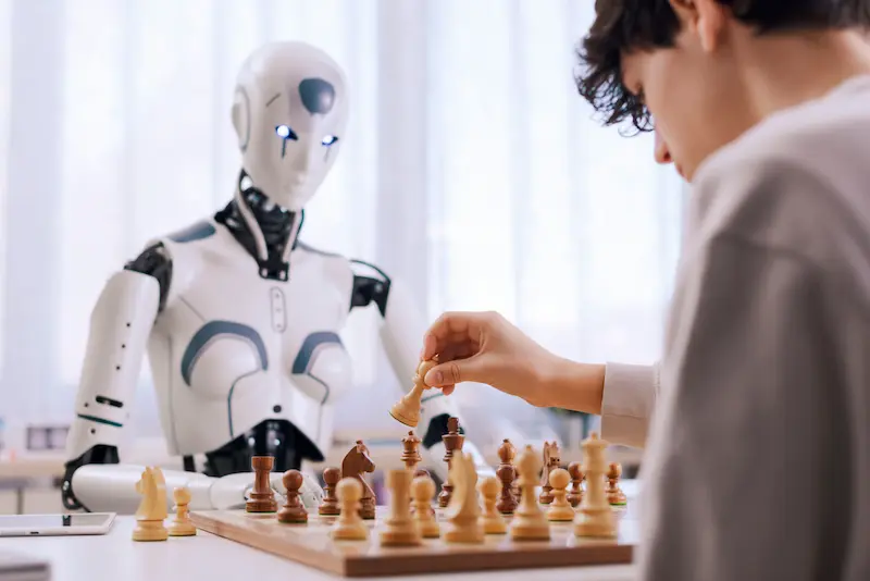 Teen playing chess with a futuristic white robot at home.