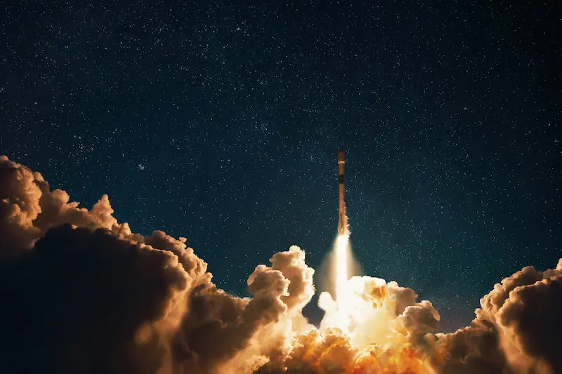 Rocket launching into the night sky filled with stars.