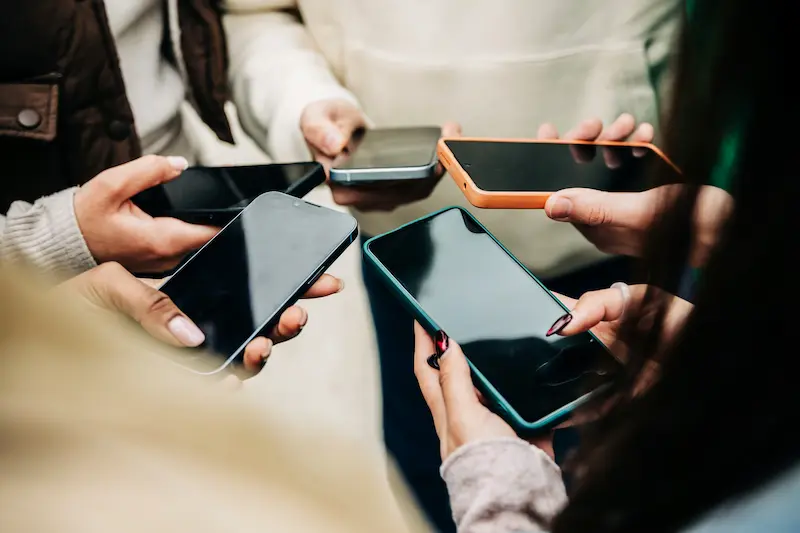 Group of people holding their cell phones together in a circle.