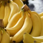 Several clusters of ripe, yellow bananas at a market.