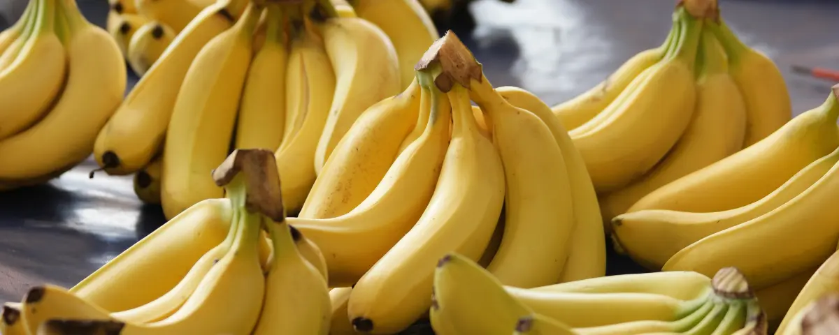 Several clusters of ripe, yellow bananas at a market.
