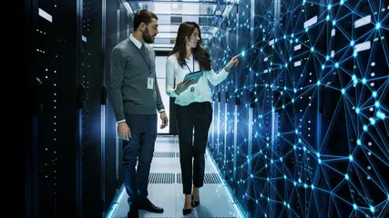 Two software engineers walking through a server room.